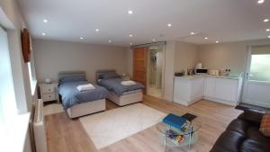 sala de estar con 2 camas y cocina en The Garden Room, 1 Heath Cottage en Knutsford