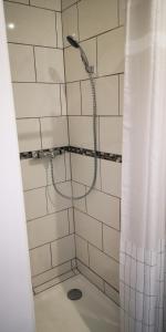 een douche met een douchegordijn in de badkamer bij La Cour du Puits, chambre Colyn in Cormeilles