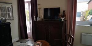 a living room with a tv on a dresser at La Cour du Puits, Chambre Earl Grey in Cormeilles