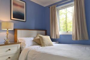 a blue bedroom with a bed and a window at Driftwood Cottage in Uny Lelant