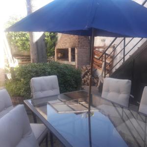 einen Tisch mit einem blauen Regenschirm auf einer Terrasse in der Unterkunft CABAÑAS VILLA CLUB 2 cerca de aeropuerto El Palomar in Hurlingham