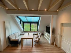 ein Wohnzimmer mit einem Tisch, einem Sofa und einem Fenster in der Unterkunft Etzel-Lodge Weideblick in Friedeburg