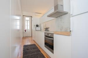 a white kitchen with a stove and a refrigerator at Liiiving In Porto | Bolhão Market Apartments in Porto