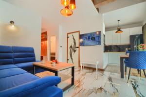 uma sala de estar com um sofá azul e uma mesa em Apartament Marmurowy w Szczyrku z widokiem na góry z dostępem do sauny i jacuzzi w weekendy, dwa miejsca parkingowe em Szczyrk