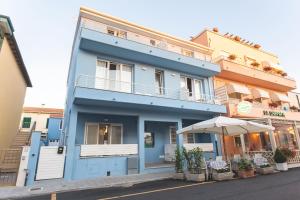 a blue building with an umbrella on a street at Albergo La Lampara in Marina di Cecina