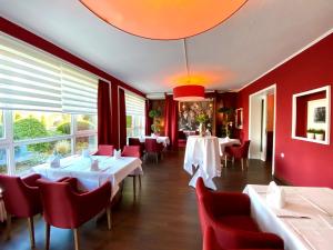 a restaurant with white tables and red chairs at Parkhotel Bielefeld in Bielefeld