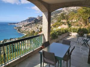 uma mesa e cadeiras numa varanda com vista para o oceano em Soutariba em Roquebrune-Cap-Martin