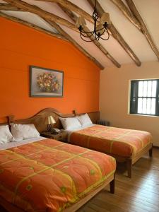 Duas camas num quarto com paredes cor de laranja em Amerindia em Cusco