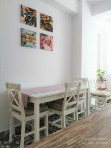 uma mesa de jantar branca com 2 cadeiras e um balcão rosa em Cozy Apartment Bujorilor Suceava em Suceava