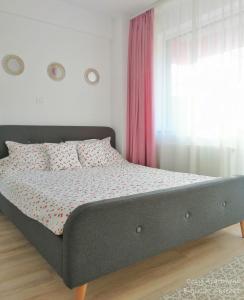 a bed in a bedroom with a pink curtain at Cozy Apartment Bujorilor Suceava in Suceava