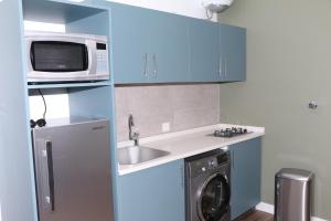 a kitchen with blue cabinets and a washing machine at Mandaren Suites in Taif
