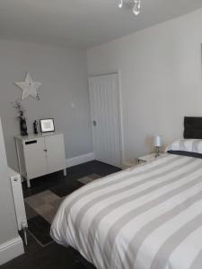 a white bedroom with a bed and a table at Amble Holiday Home in Amble