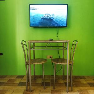 a table with two chairs and a television on a green wall at Blue Nest Apartment in Manila