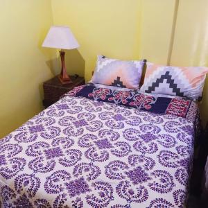 a bed with a purple and white comforter and a lamp at Blue Nest Apartment in Manila