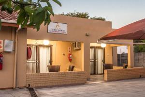 un restaurant avec des tables et des chaises en face d'un bâtiment dans l'établissement APICAL GUESTHOUSE, à Maun