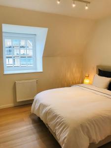 a bedroom with a white bed and a window at EastDune in Oostduinkerke