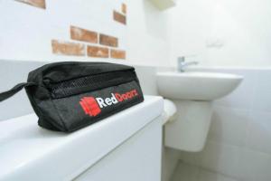 メダンにあるRedDoorz near Ringroad City Walks Medanの洗面台横のカウンターに座る黒い袋