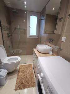 La salle de bains est pourvue d'un lavabo et d'un lave-linge. dans l'établissement Апартаменти Анджело, à Paralía Avdhíron
