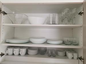 un armario blanco lleno de platos, tazones y vasos en Апартаменти Анджело en Paralía Avdhíron
