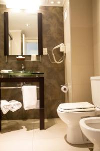 a bathroom with a toilet and a sink and a mirror at Golf Apartamentos in Montevideo