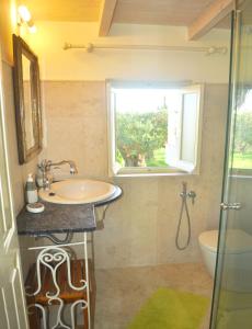 baño con lavabo y ventana en Lemoni Apartments, en Pelekas
