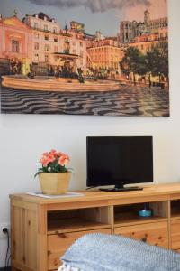 a television on a desk with a painting on the wall at Aurora Sky in Porto