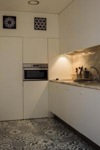 una cocina con armarios blancos y fregadero en Aurora Sky, en Oporto