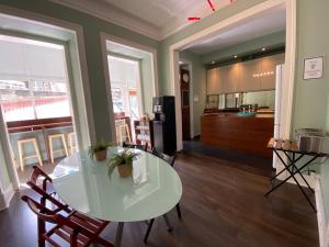 a dining room with a white table and a kitchen at Green Heart Hostel in Lisbon