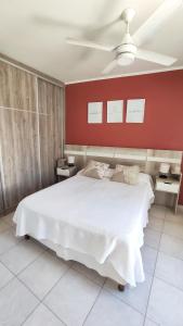 - une chambre avec un lit blanc et un mur rouge dans l'établissement BellaVista Departamento Temporario, à Paraná