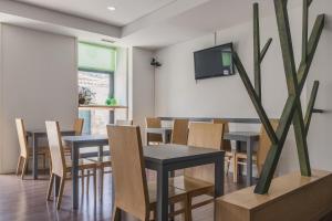 uma sala de jantar com mesas e cadeiras e uma TV em Hotel Comércio em Resende