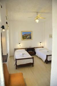 a room with two beds and a ceiling fan at Filoxenia Villa in Koutsounari