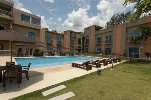 a swimming pool with a table and benches next to a building at Hotel Natural Hill's by H&R in Villeta