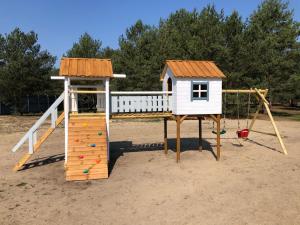 a playground with a house and a slide at Kwiejcówka in Kwiejce