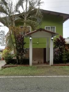 une maison verte avec un garage dans l'établissement Ofiuras Hostal, à Colón