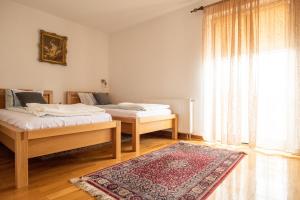 two beds in a room with a rug and a window at Kuća za odmor Vallirea in Kaptol