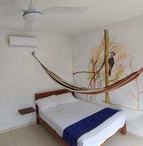 a room with a bed with a bird painting on the wall at La Casa de las Aves in Bacalar