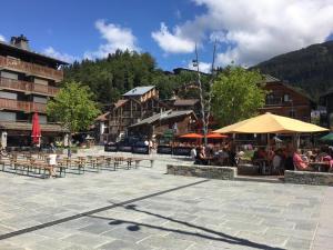 un grupo de mesas y sombrillas en una plaza con edificios en Les Carroz d'Araches, en Les Carroz d'Araches