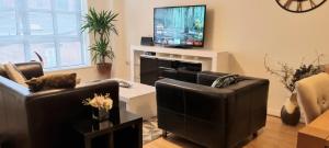 a living room with two couches and a flat screen tv at Elite luxury apartment in Birmingham