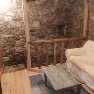 a room with a stone wall with a couch and a bench at Casa Branca in Lousã