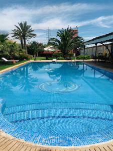 a large blue swimming pool with palm trees in the background at Equi Palace & SPA Near Aeroport in Berrechid