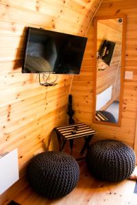 a room with a tv and two ottomans and a mirror at Log cabin in Kells