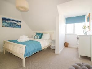 a white bedroom with a bed and a window at Offshore in Newquay