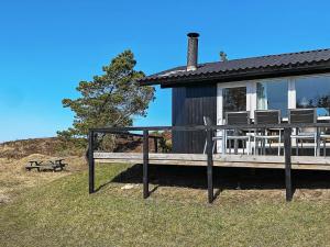 ein Haus mit einer Terrasse mit Stühlen und einer Bank in der Unterkunft 6 person holiday home in Oksb l in Oksbøl