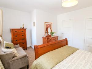 a bedroom with a bed and a chair and a dresser at Kings Cottage in Alston