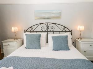 a bedroom with a bed with blue and white pillows at Shamrock Cottage in Grange Over Sands