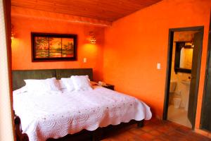1 dormitorio con 1 cama con pared de color naranja en Hotel Casablanca Natural Spa, en Paipa