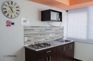 een keuken met een wastafel en een klok aan de muur bij Apartamento Faunaventura cerca Parque del Café con piscina in Montenegro +52 foto's