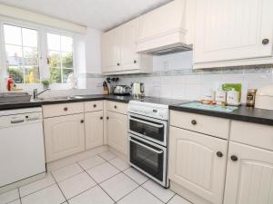 a white kitchen with white cabinets and appliances at Poppy Cottage in Charlton Marshall