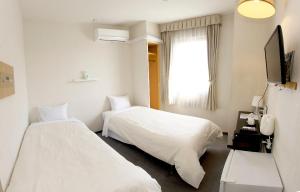 a hotel room with two beds and a window at Hotel Crown Hills Toyohashi in Toyohashi