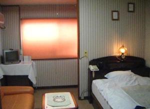 1 dormitorio con 1 cama, TV y sofá en Ryokan Seifuso, en Ōmuta